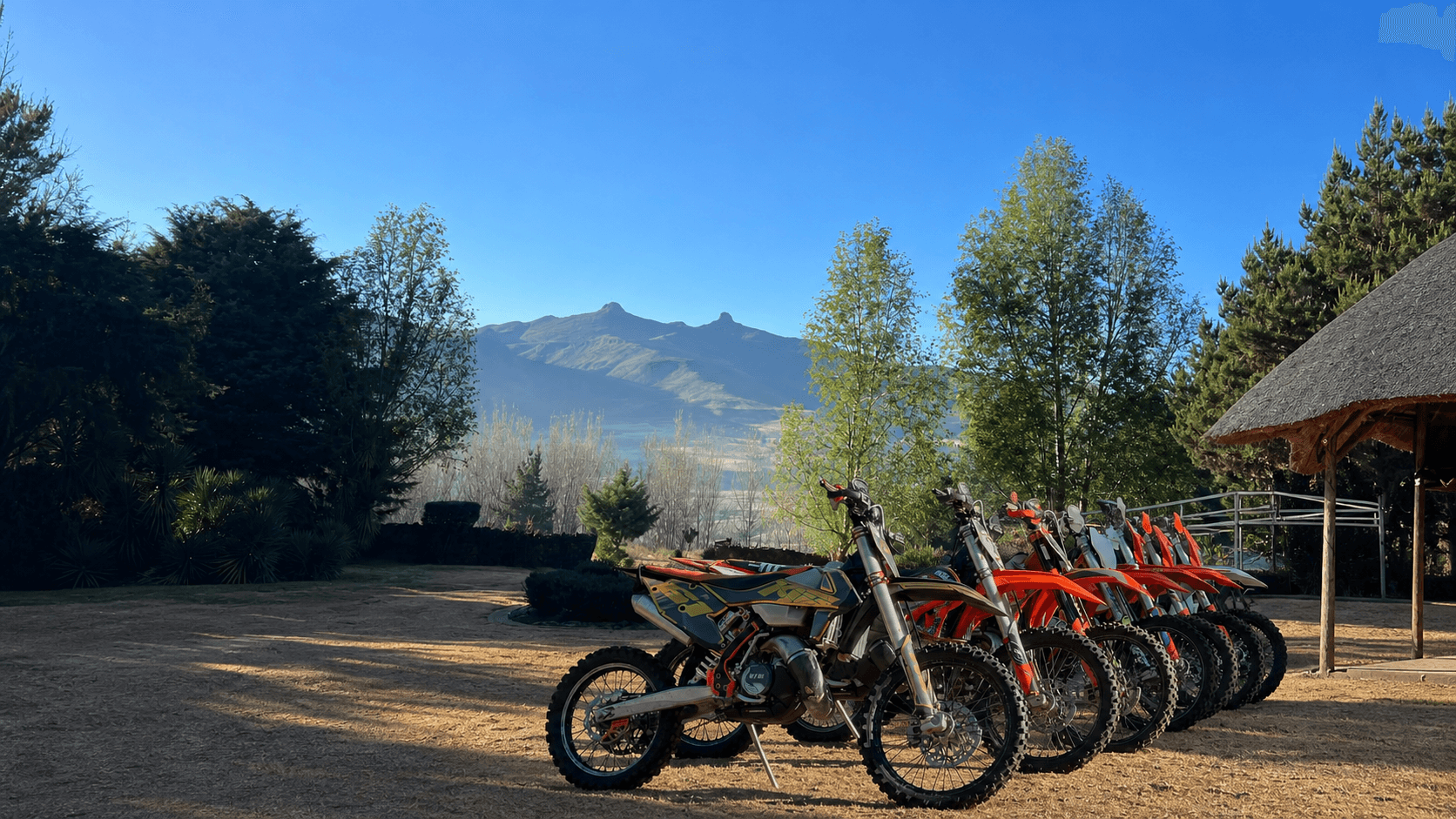 Enduro motorcycles lined up beneath Lesotho's mountain peaks