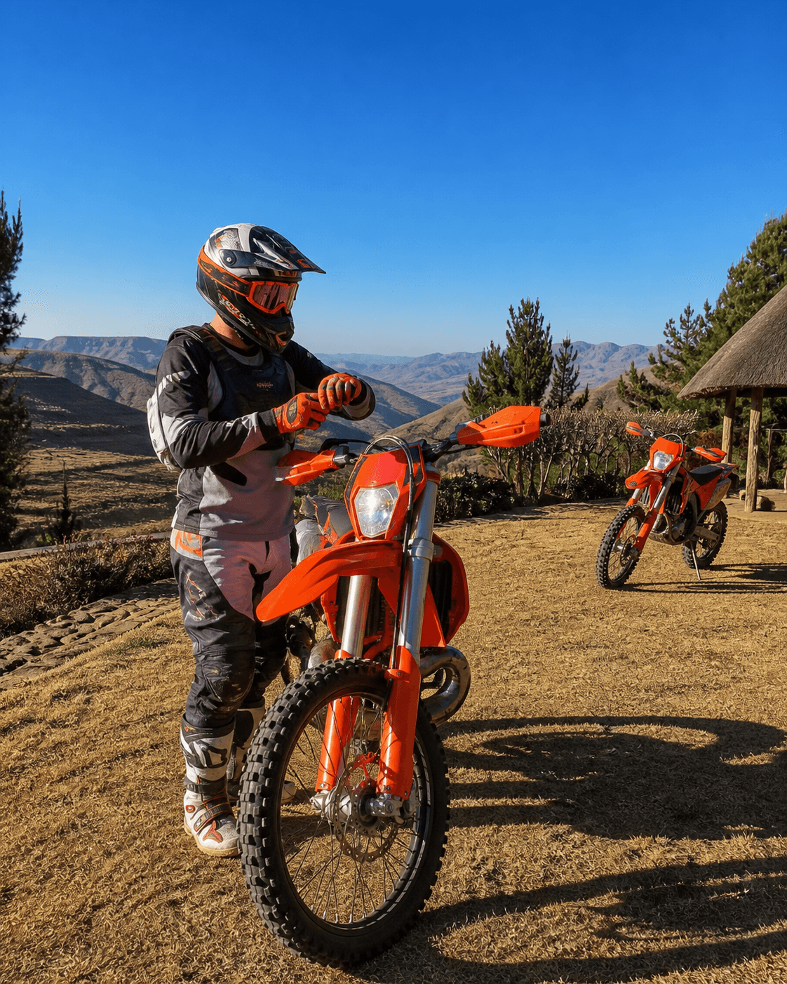 A geared rider checks their gloves beside an orange enduro motorcycle