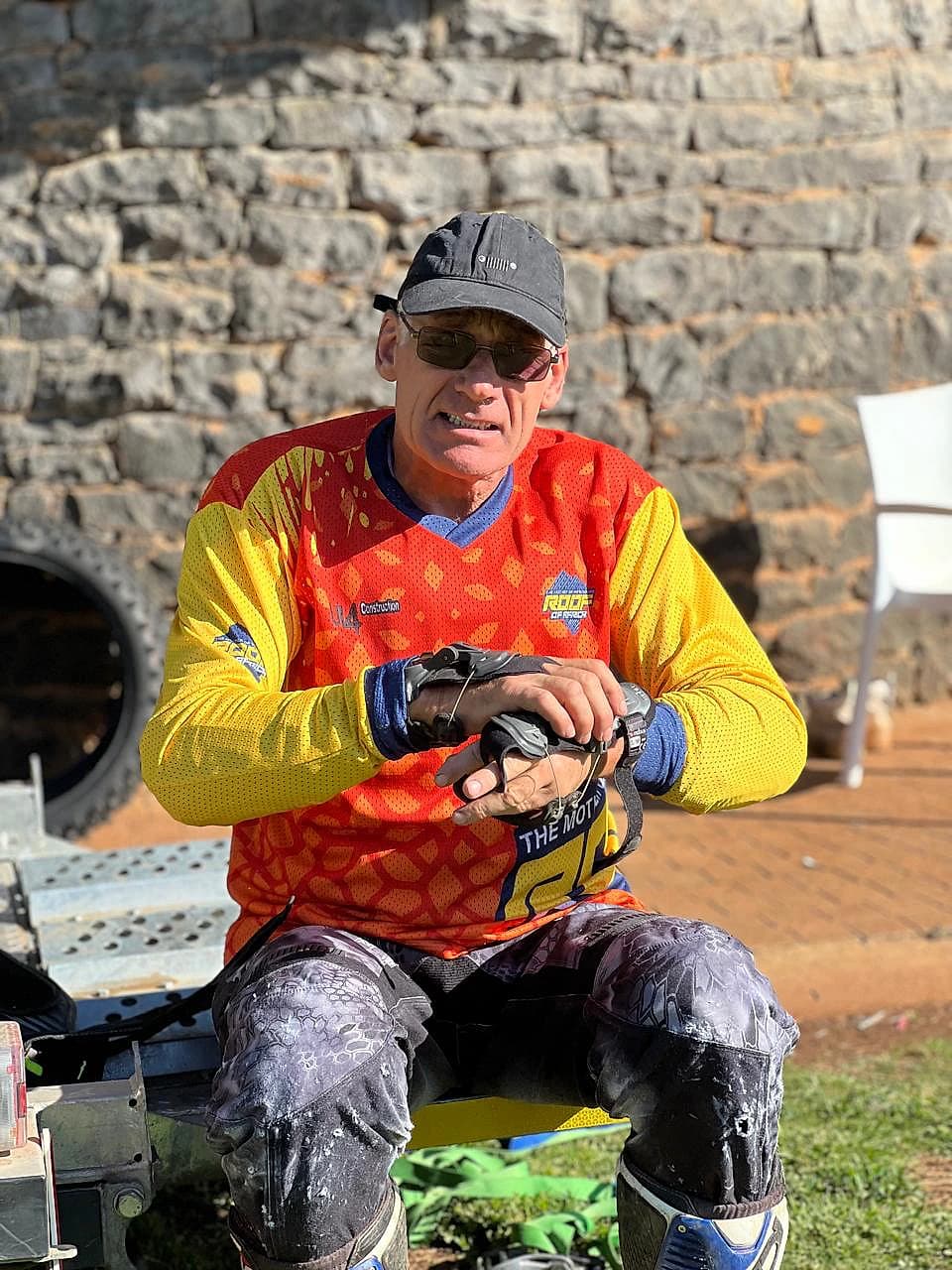 Rider seated in protective gear finishing a glove check outside the lodge