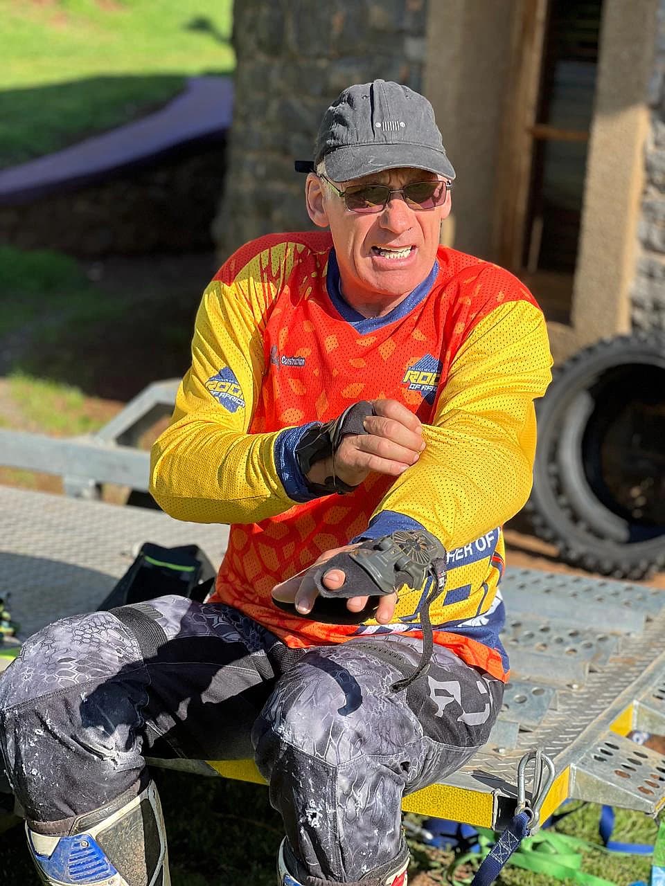 Rider in an orange and yellow jersey adjusting a glove before a ride